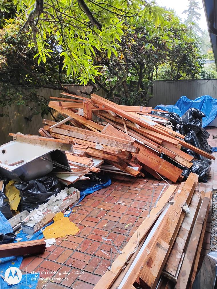 Pile of demolition lumber and a bathtub on a brick patio